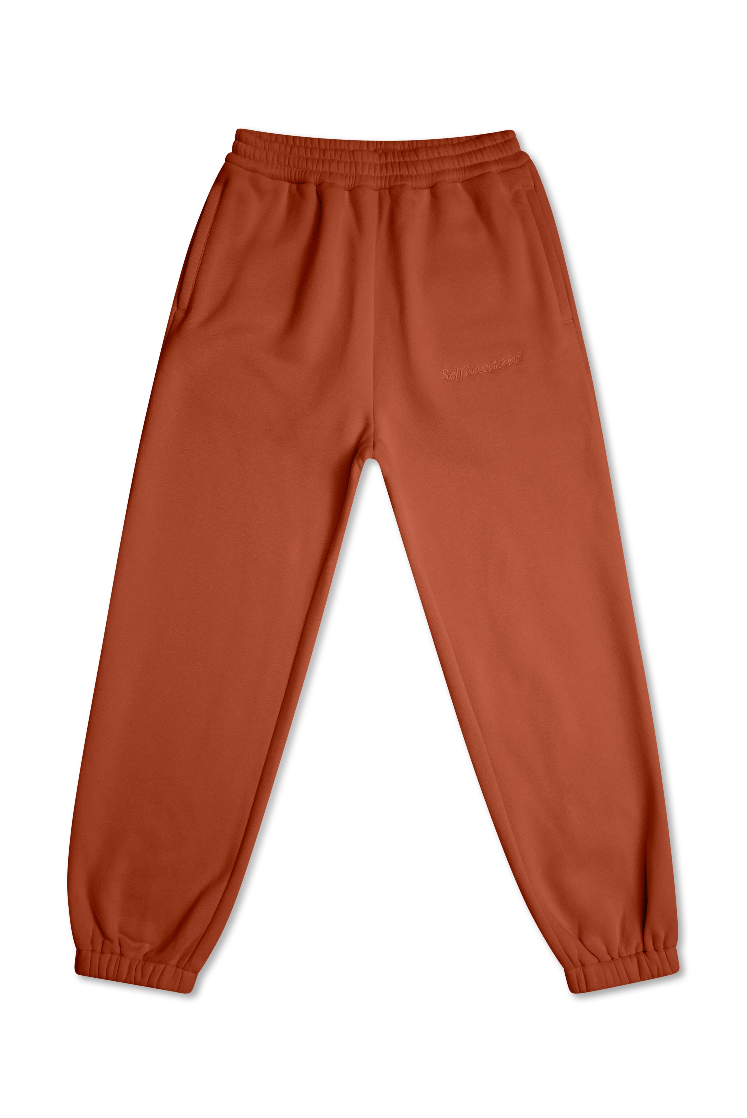 A pair of rust-colored jogger sweatpants with an elastic waistband and cuffs, laid flat against a white background.