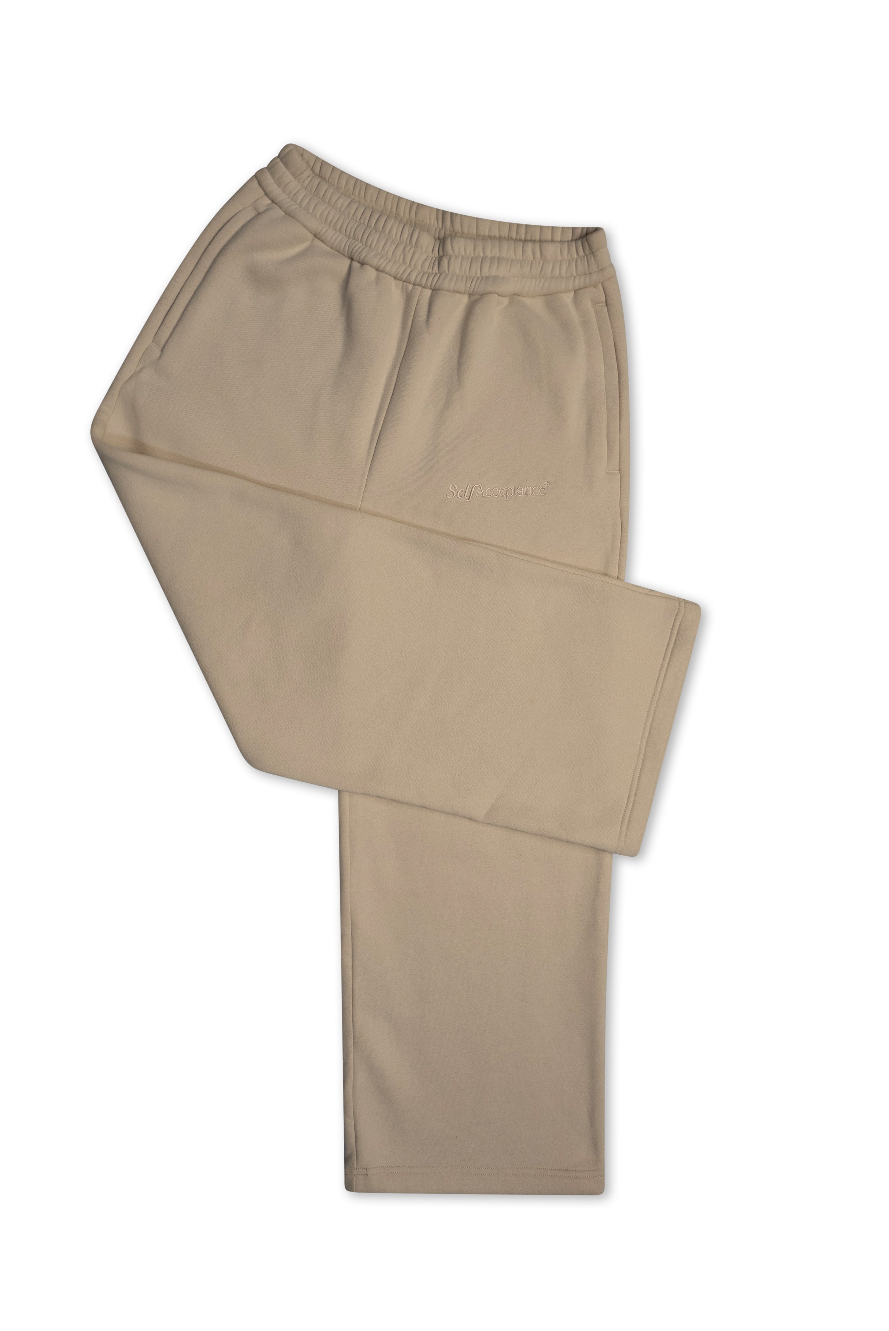 A pair of creamy athletic pants with an elastic waistband and a small script logo on the left thigh, displayed against a plain white background.