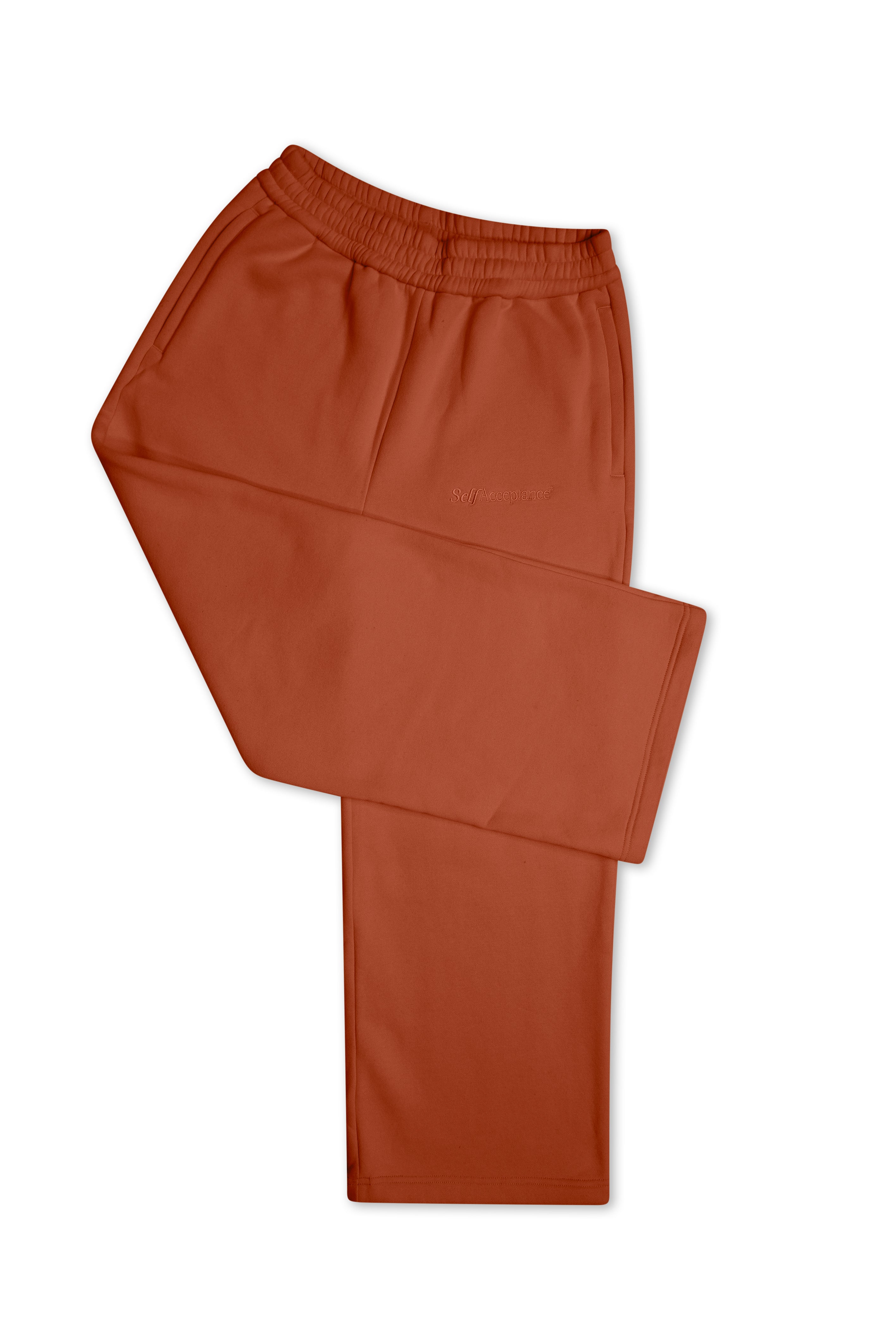 A pair of rust-colored lounge pants folded neatly on a solid white background.
